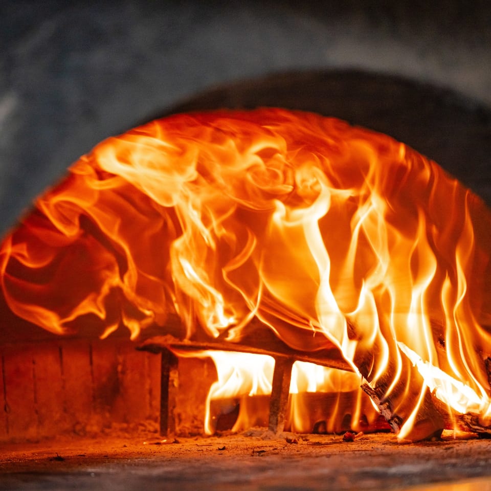 Flames burning inside the wood-fired pizza oven.