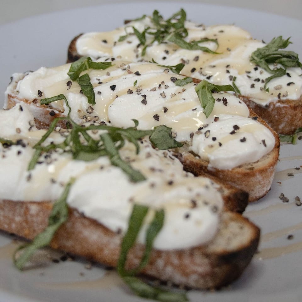 Creamy cheese toast topped with herbs and black pepper.